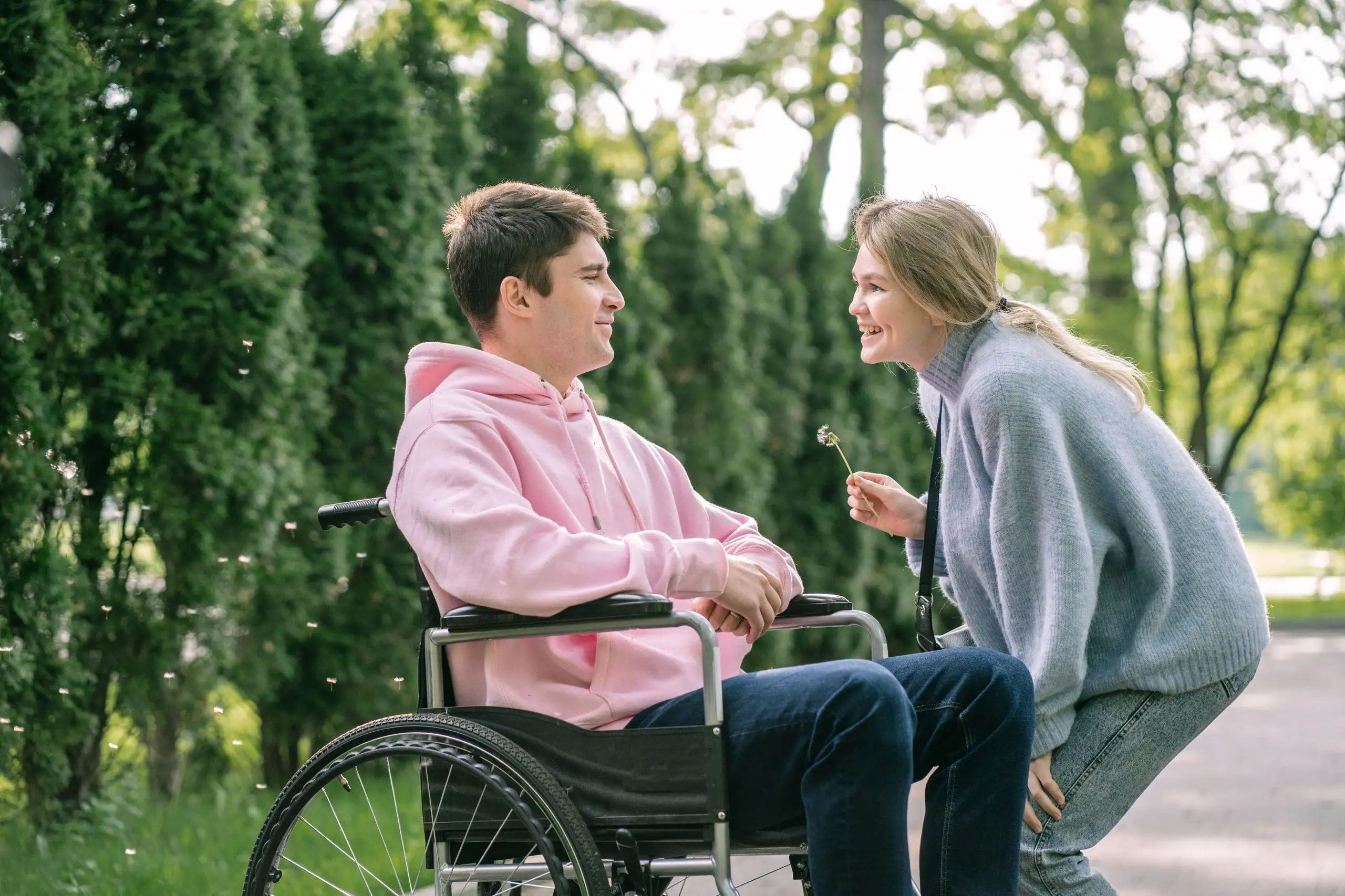 A young man in a wheelchair sharing a laugh with a friend in a park