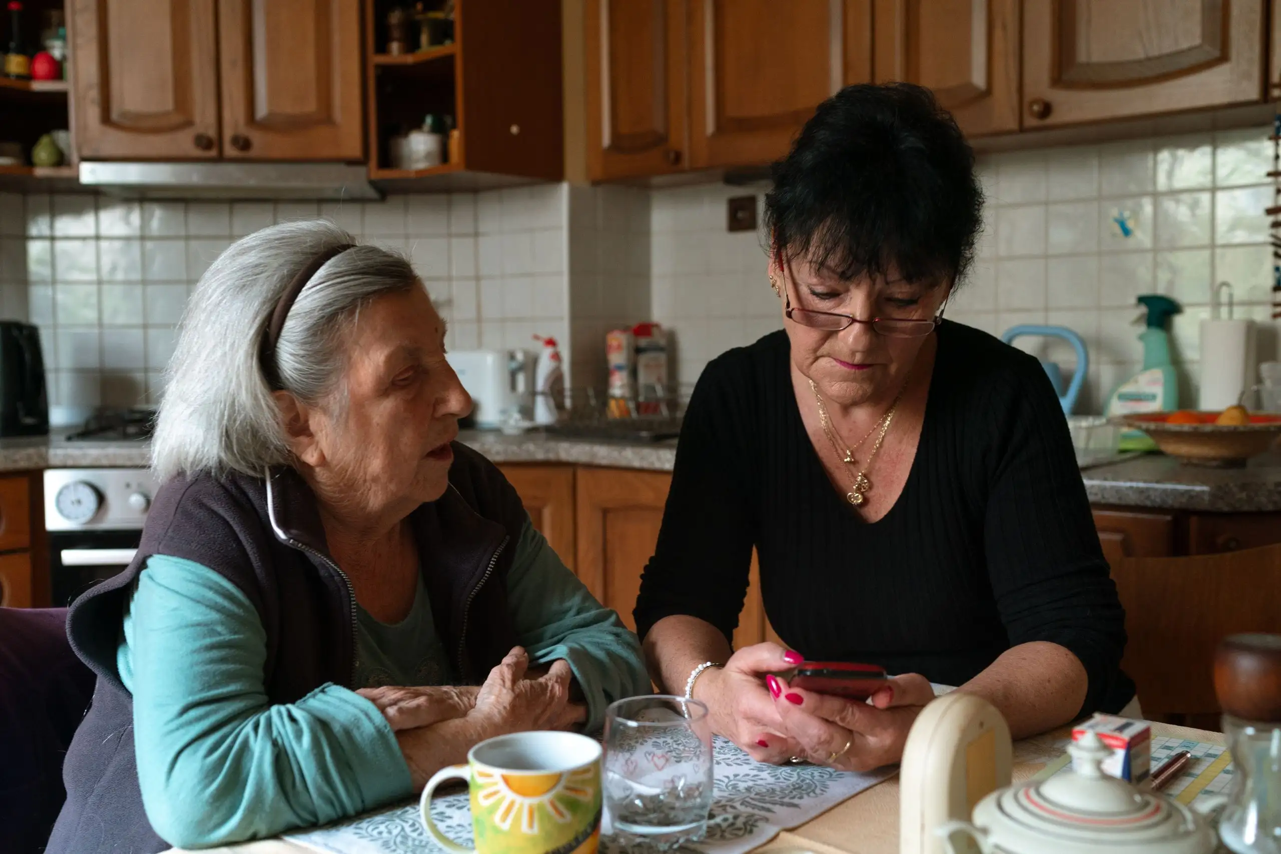 An older woman and a younger woman talking at a kitchen table
