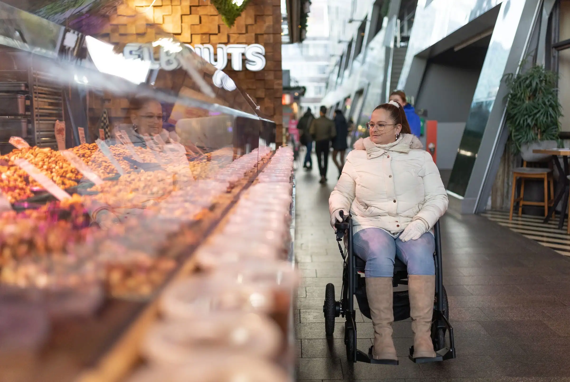 A woman in a wheelchair browsing a food stall at an indoor market